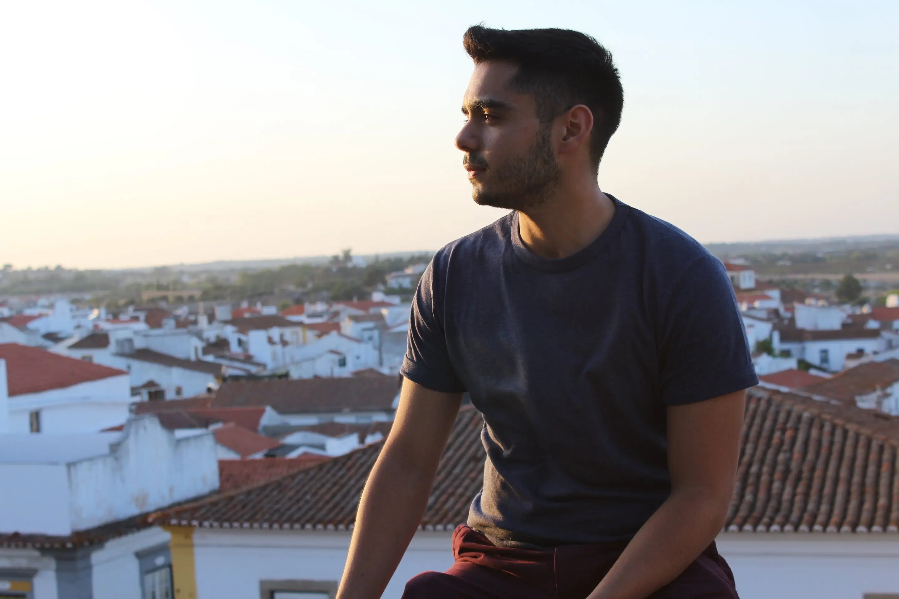 Andrés Adriani de perfil al atardecer, sentado sobre los tejados blancos de un pueblo.